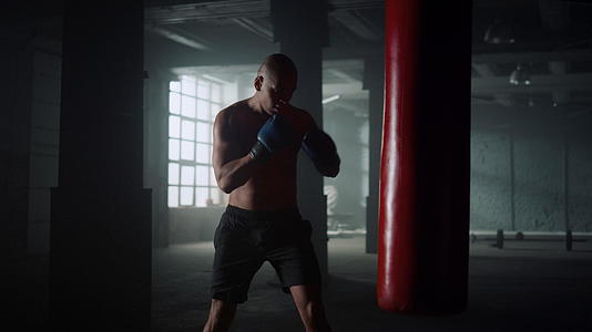 拳击手在健身房的沙袋上练习踢腿视频的预览图