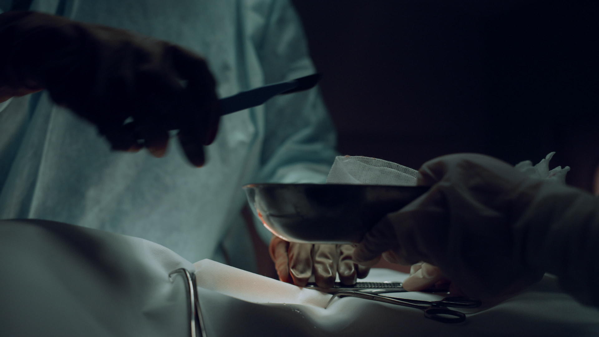 外科医生用手术刀在黑暗的医院病房里做切口视频的预览图