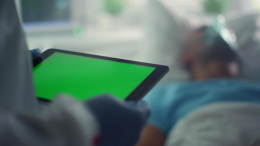 医生在病床上用绿屏平板屏幕特写病人的氧气面罩视频的预览图