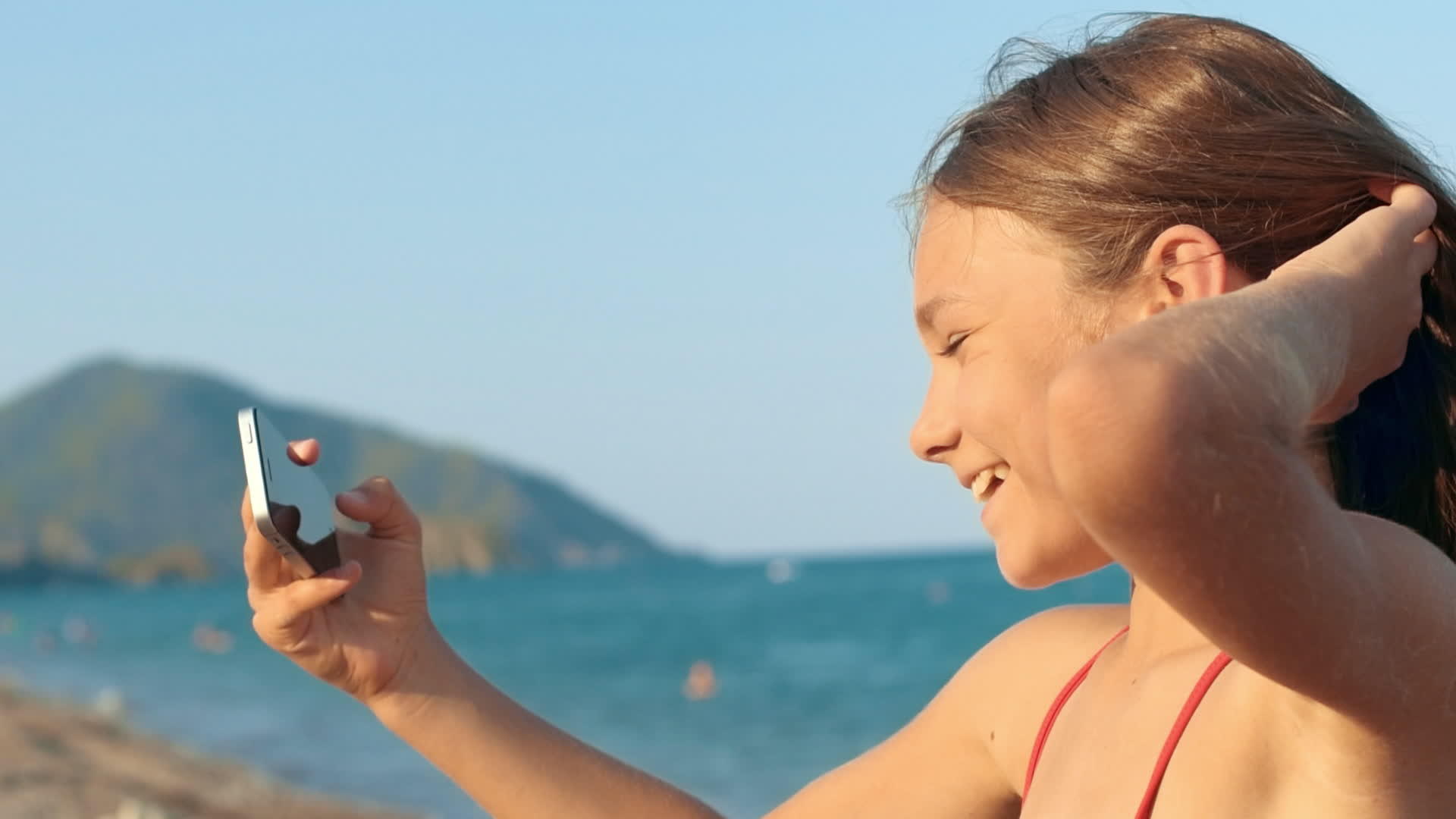 小女孩暑假在海边看手机视频的预览图