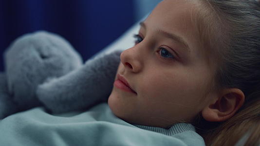 女孩带着毛绒玩具躺在病床上在儿科医院检查视频的预览图