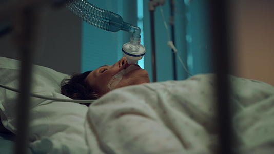 一个戴着氧气面罩肖像的病妇躺在病房里视频的预览图