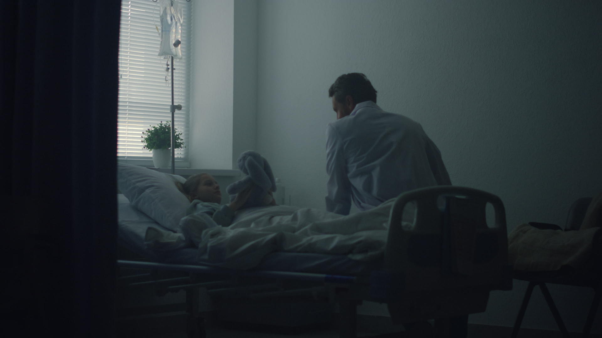医生在诊所病房看望小病人生病的女孩拿着一个毛绒玩具在床上视频的预览图
