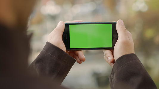 男人在户外用绿屏手机聊天视频的预览图
