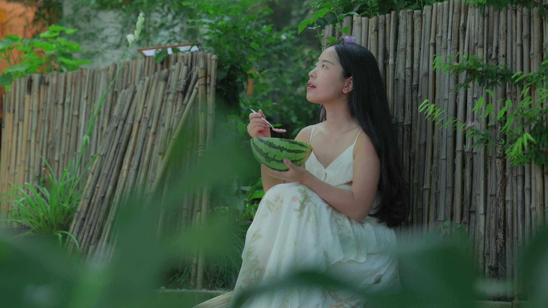 夏天竹篱园里吃西瓜的女孩视频素材视频的预览图