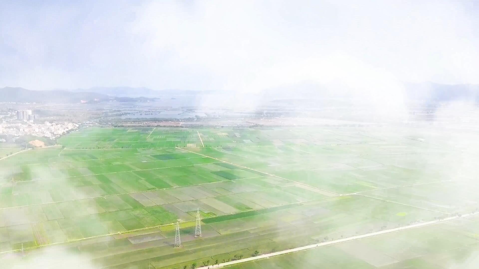 航拍穿过云层看到邻海农村开阔田野视频的预览图