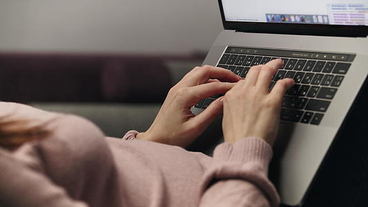 女人用手在膝盖上的电脑键盘上打字视频的预览图