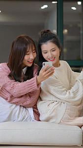 两个女生靠在一起玩手机视频的预览图