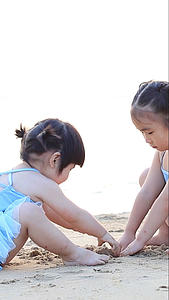 夏日夕阳下儿童在海边沙滩上玩沙子视频的预览图