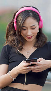 时尚女性戴耳机玩手机视频的预览图