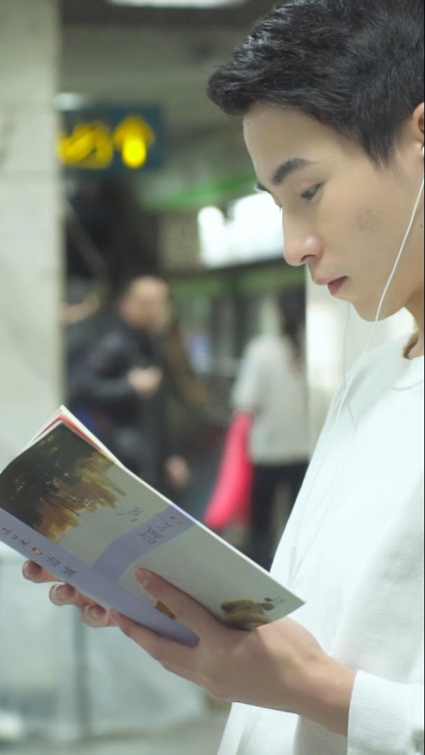 男青年在地铁站着看书视频的预览图