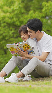 爸爸和孩子在树下看童话故事书视频的预览图