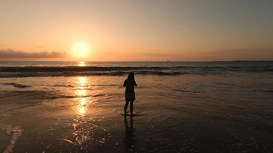 4K落日时海边独自听海的女生背影视频素材视频的预览图
