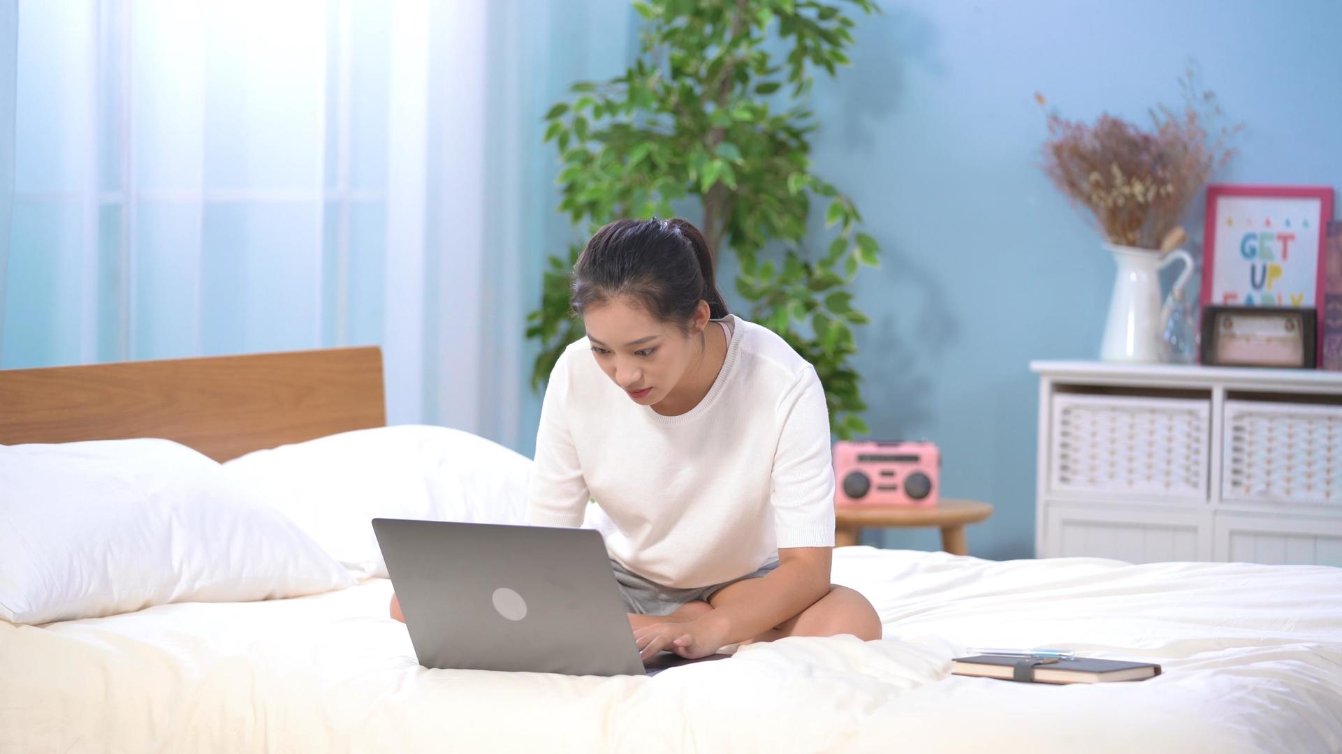 4k居家女性坐在床上使用电脑视频的预览图