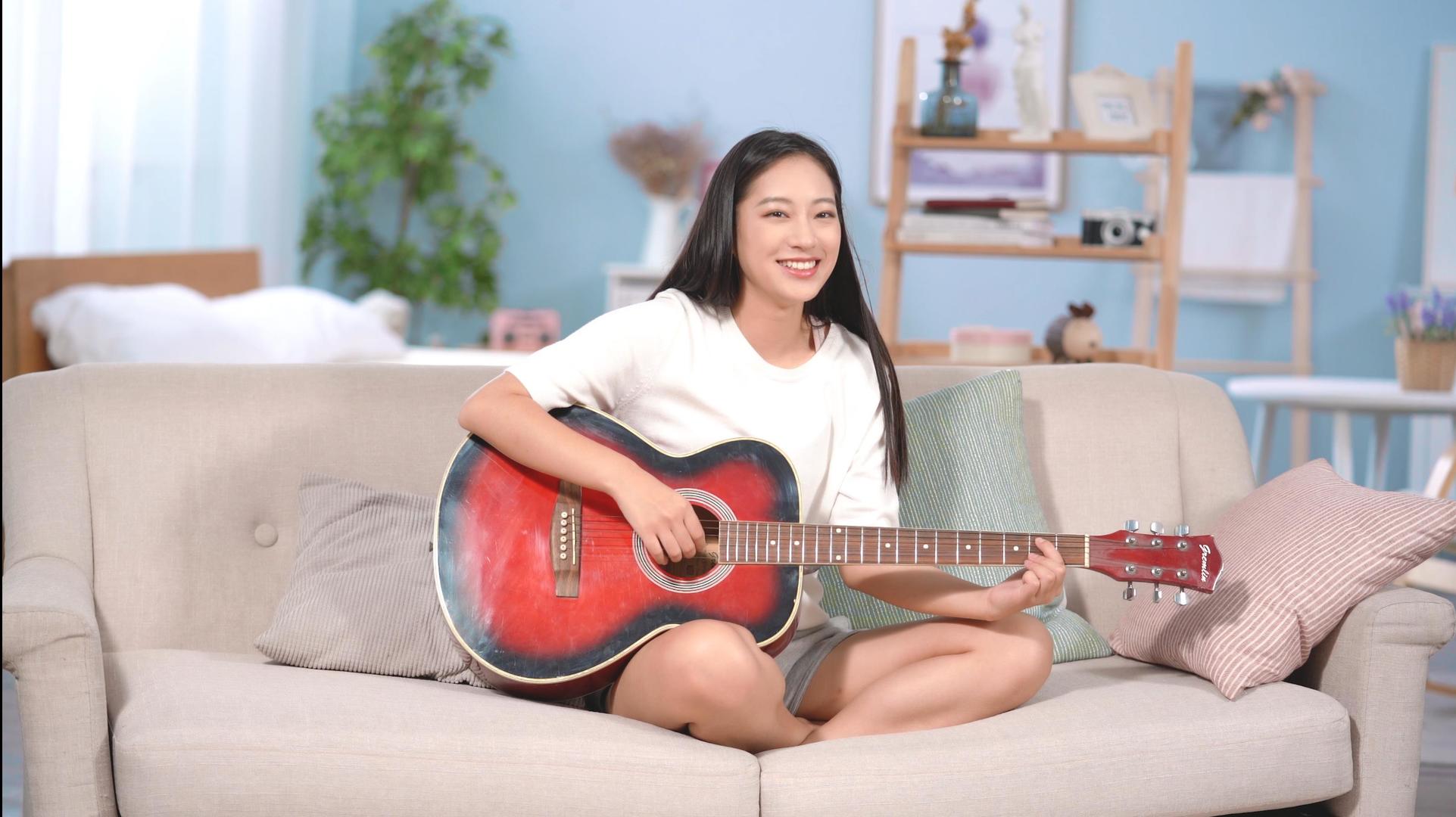 4k可爱女生盘腿坐在沙发上弹吉他视频的预览图