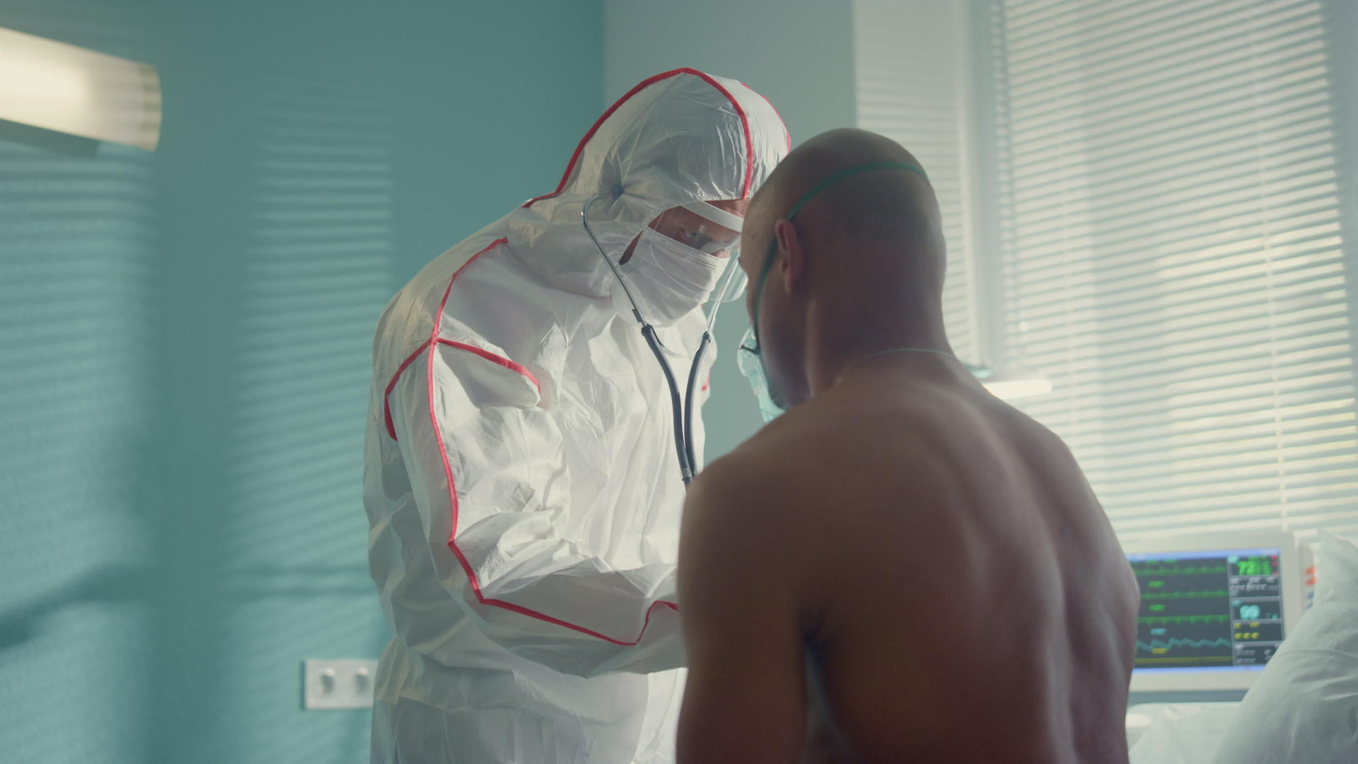 穿着防护服的医生在医院用听诊器检查男性病人视频的预览图