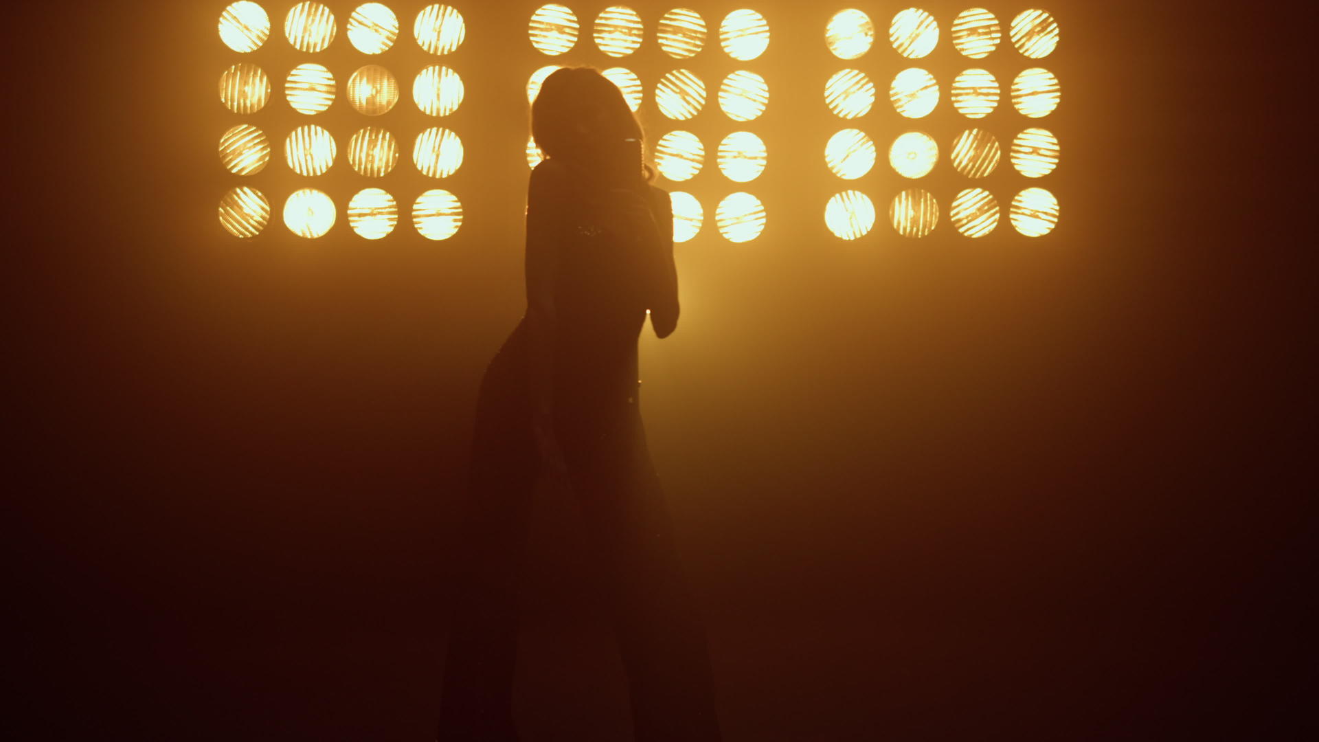 年轻女歌手在灯光下用复古麦克风跳舞唱歌视频的预览图