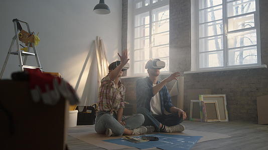 这对年轻夫妇坐在地板上用VR眼镜上规划新家装修效果视频的预览图