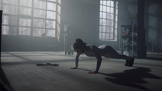 女性在健身房的地板上做俯卧撑来训练腹部肌肉视频的预览图