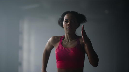 女运动员在健身房黑暗的走廊里快速奔跑视频的预览图