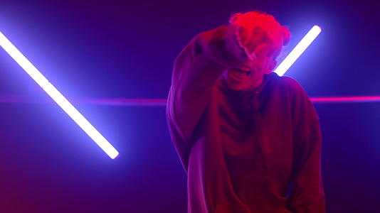 女孩嘻哈舞者在紫外线背光舞台上表演舞蹈视频的预览图