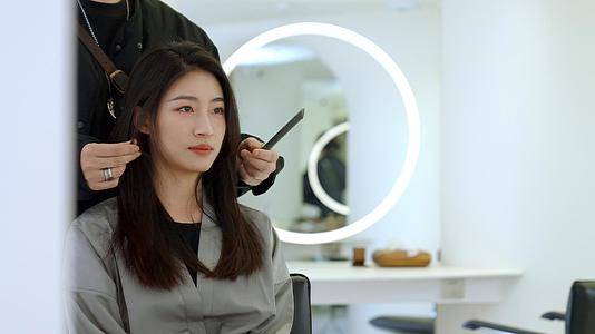 女顾客通过镜子看发型师给自己做造型视频的预览图