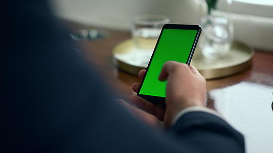 男性手动滚动绿色智能手机屏幕特写视频的预览图