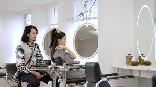 女顾客边梳理自己头发边和发型师交流视频的预览图