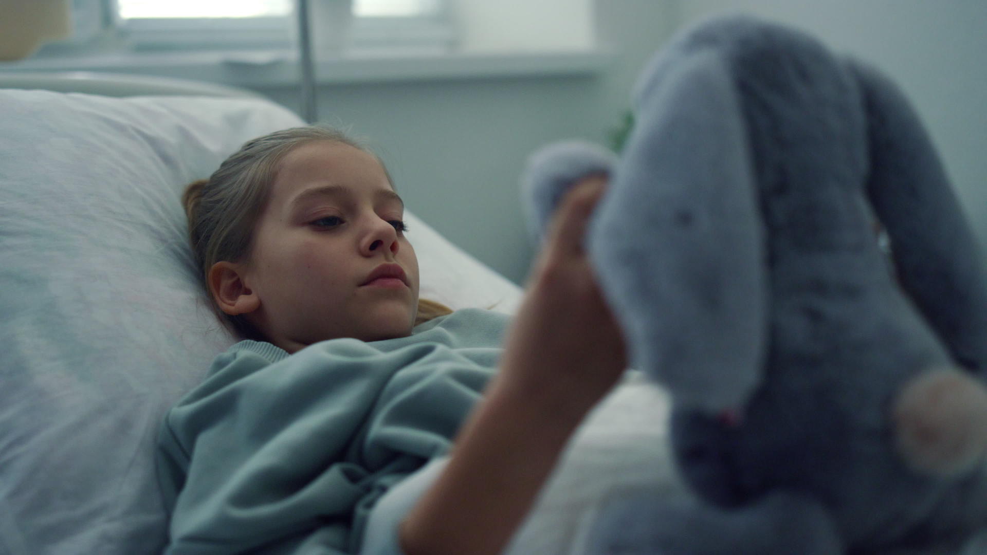 心烦意乱的女孩独自躺在医院的病床上玩毛绒玩具视频的预览图