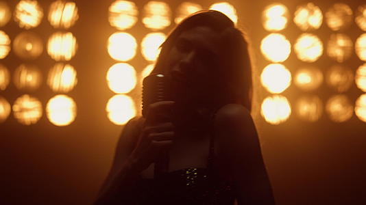 舞台上用麦克风唱歌的优雅性感女歌手视频的预览图
