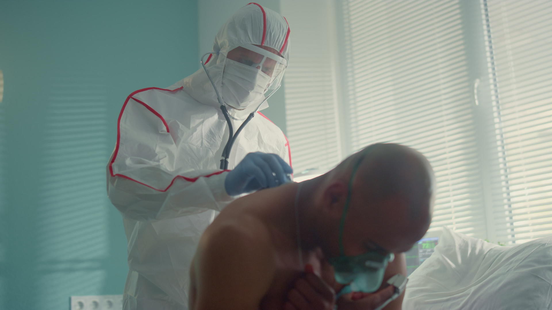医生戴着防护服面罩用听诊器检查感染患者的背部视频的预览图