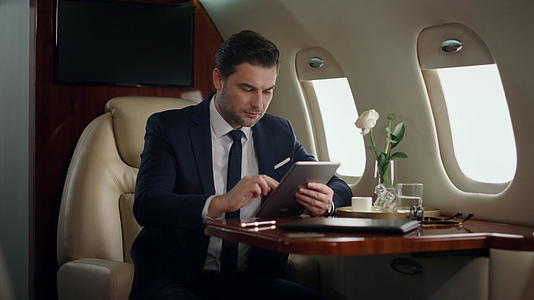 男白领在豪华喷气式飞机上用平板电脑工作视频的预览图