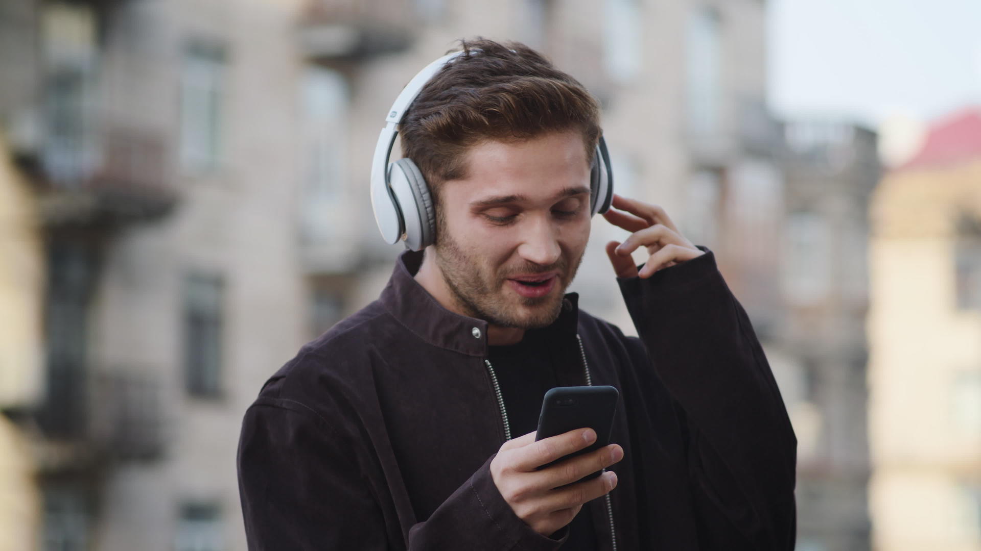 年轻男性在户外用耳机听歌舞视频的预览图