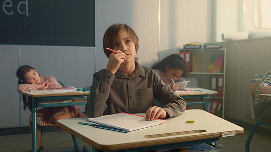 男孩坐在学校的书桌旁学习视频的预览图