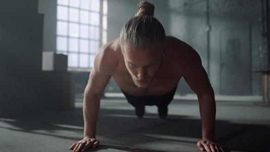 男人在健身房的地板上做俯卧撑来训练腹部肌肉视频的预览图