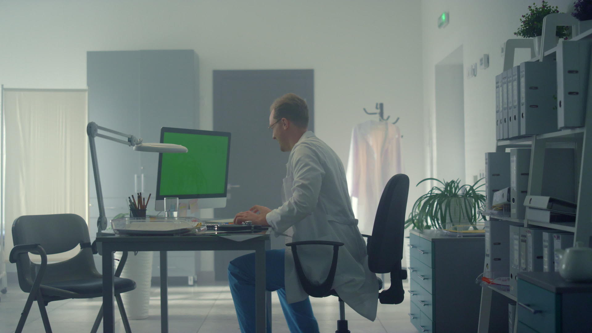 医生在办公室的绿屏现代电脑前工作视频的预览图