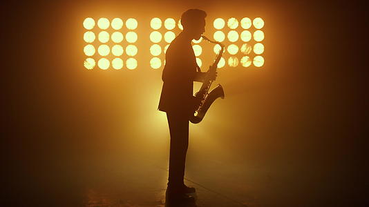 剪影爵士音乐家在聚光灯下演奏萨克斯管视频的预览图