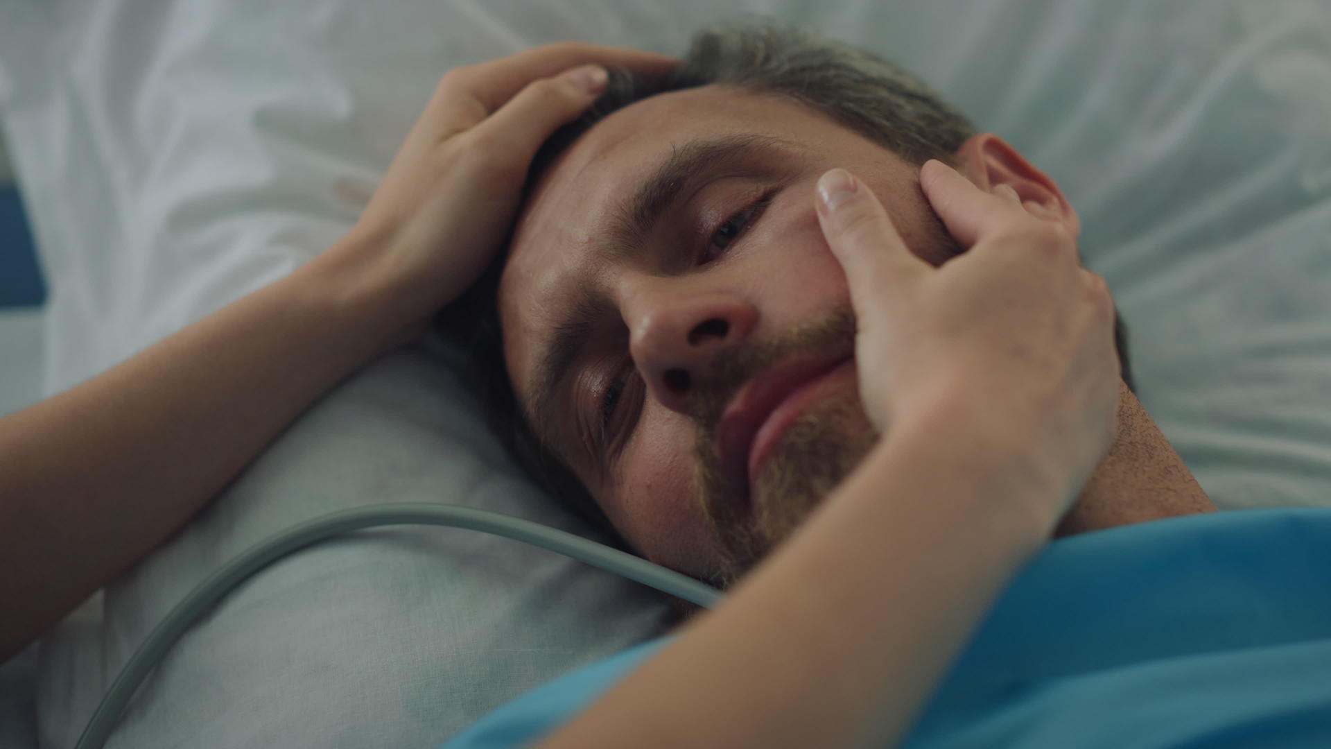 手术治疗特写后疲惫的患者躺在床上家人摸了摸脸视频的预览图