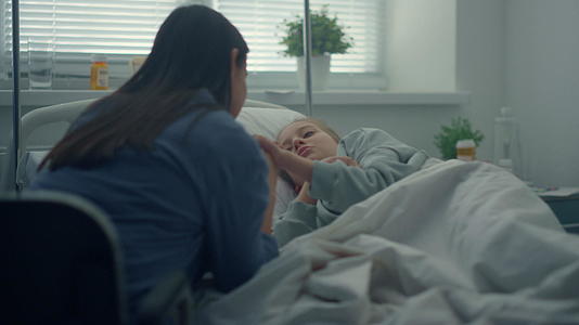 小女孩躺在病床上母亲握着孩子的手安慰她视频的预览图
