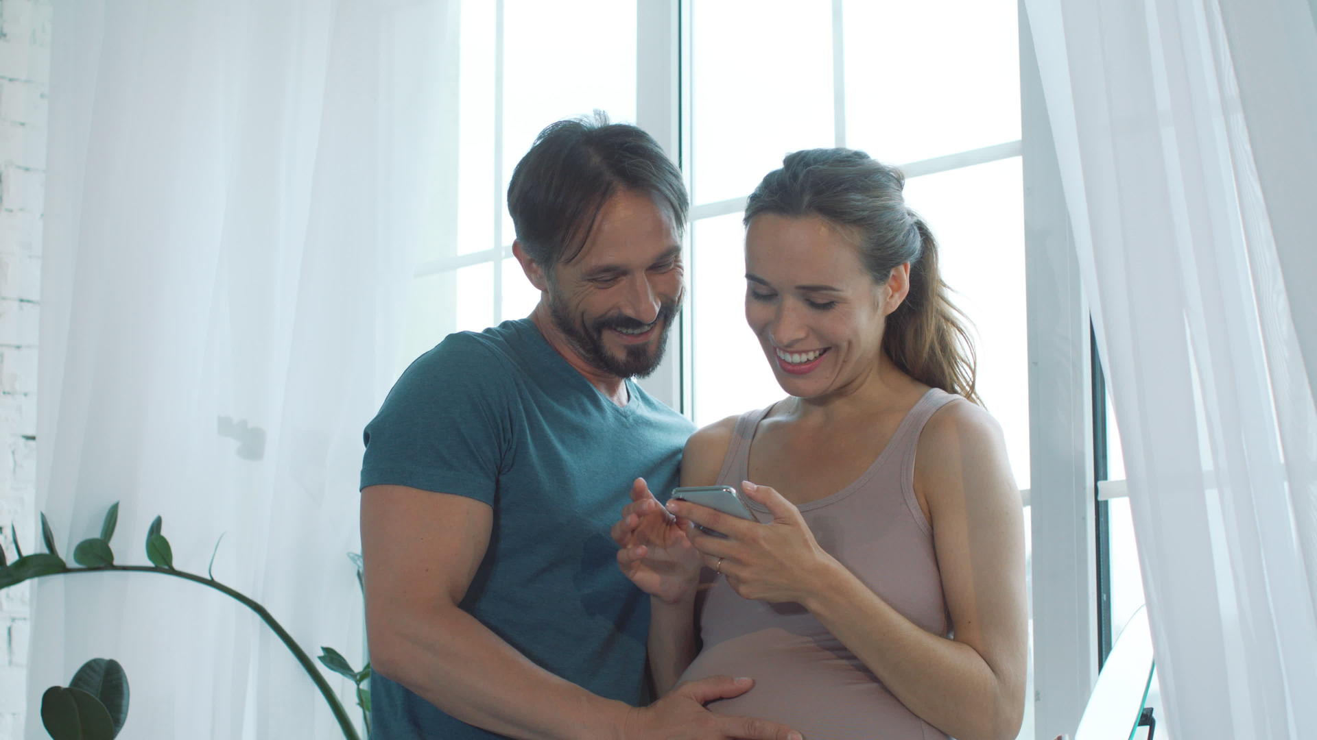 丈夫和怀孕的妻子一起看手机视频的预览图