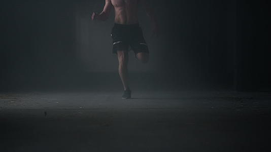 男运动员在黑暗的走廊里做体育锻炼和慢跑视频的预览图