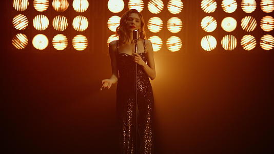 优雅的金发女歌手在聚光灯下表演独家歌曲视频的预览图