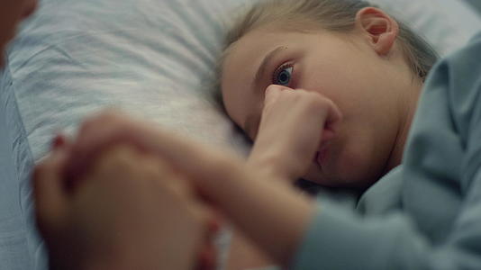 可爱的女孩躺在医院的病床上母亲轻轻地握着孩子的手特写着视频的预览图