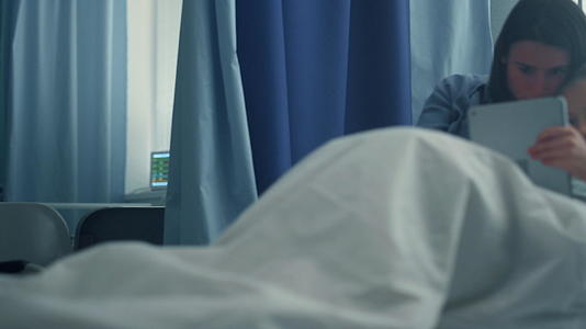 母亲陪同生病的女儿在医院病房使用平板电脑视频的预览图