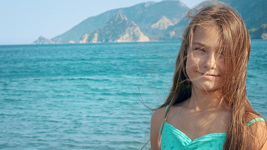 在海边度暑假的小女孩对着镜头微笑视频的预览图