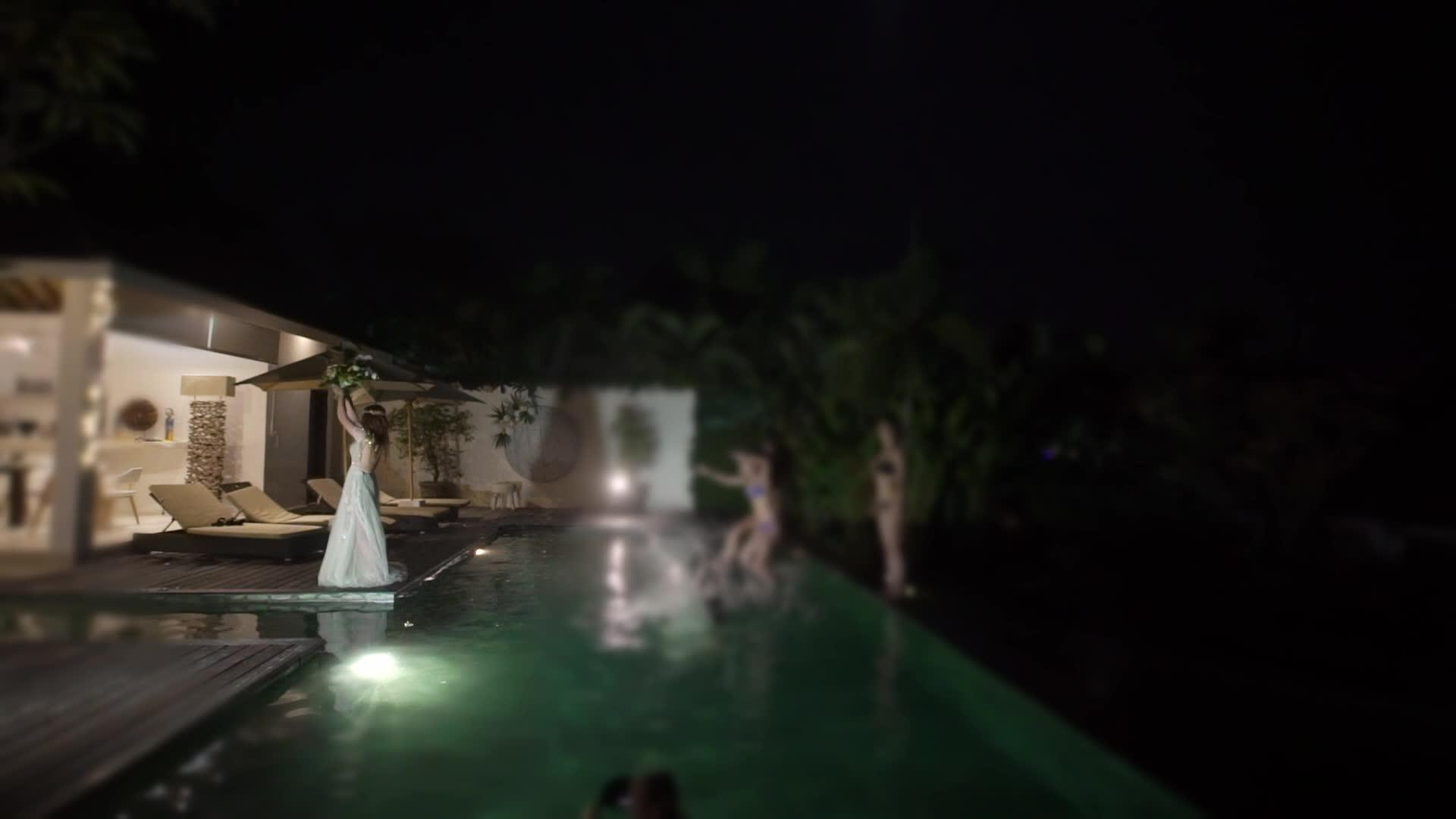 婚礼上新娘在晚上的游泳池派对上扔了一束花视频的预览图