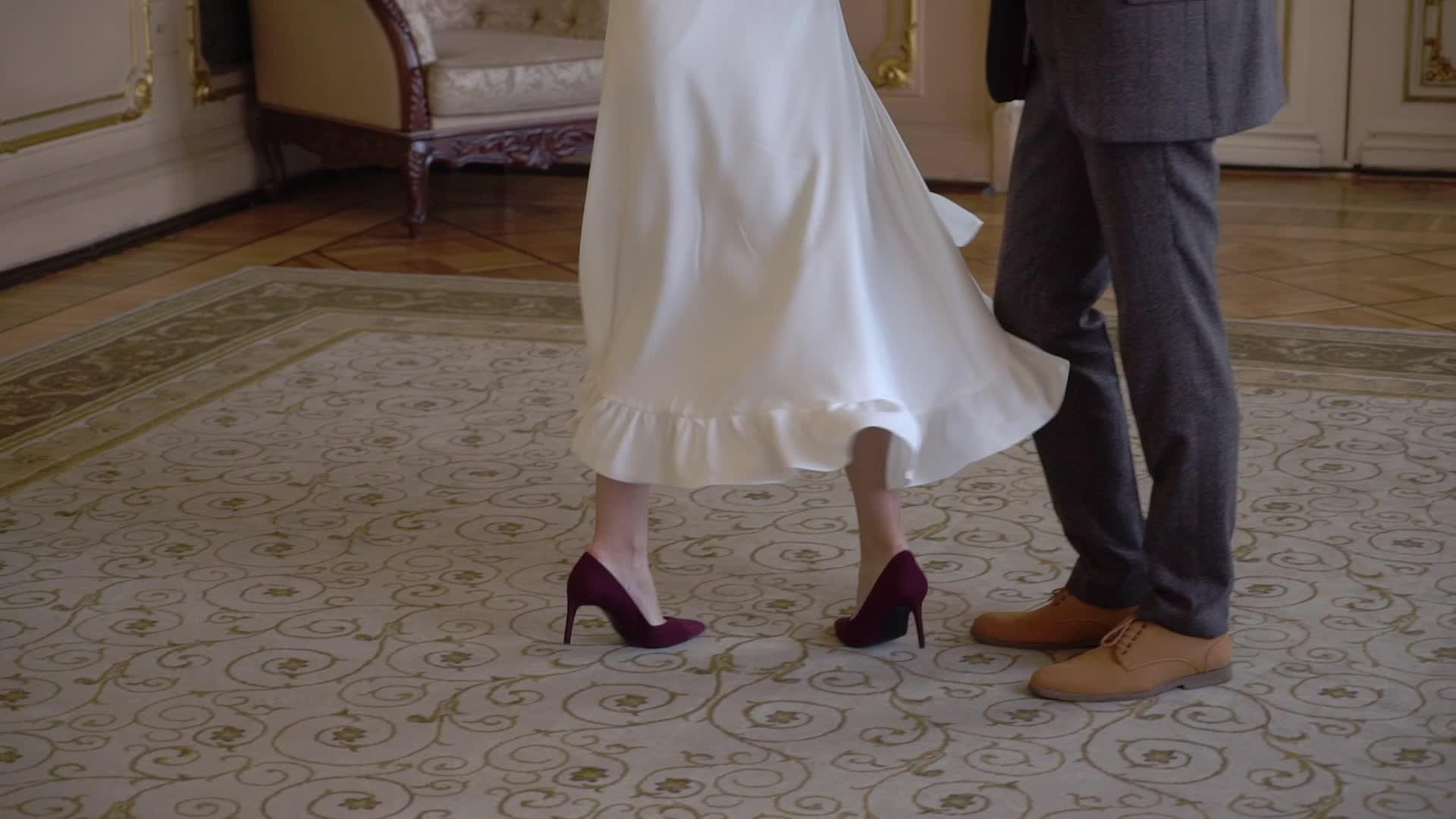 年轻的新婚夫妇在室内跳舞新娘和新郎的腿穿在地板上视频的预览图