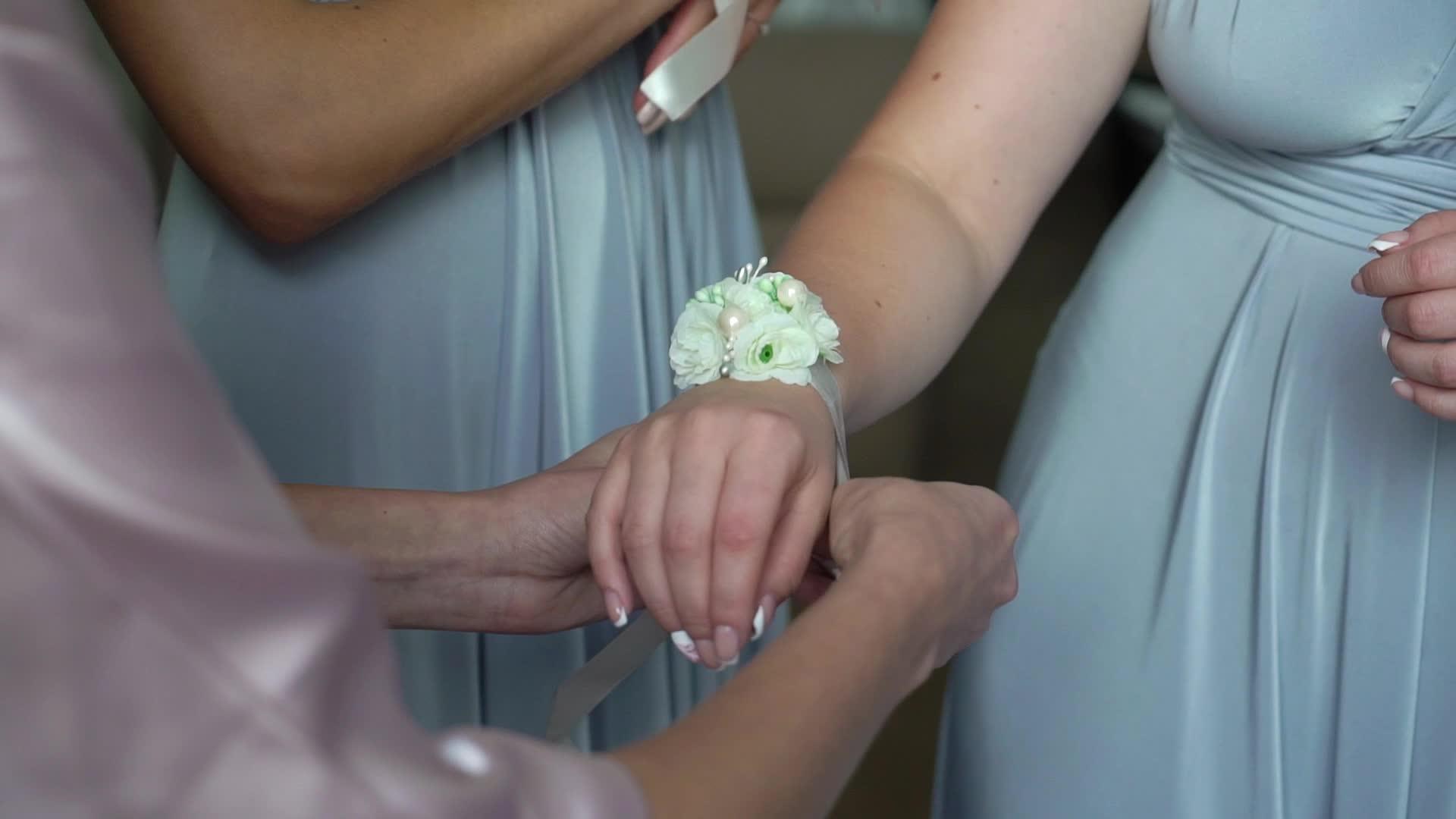 年轻的新娘在伴娘的手腕上戴上鲜花手镯视频的预览图