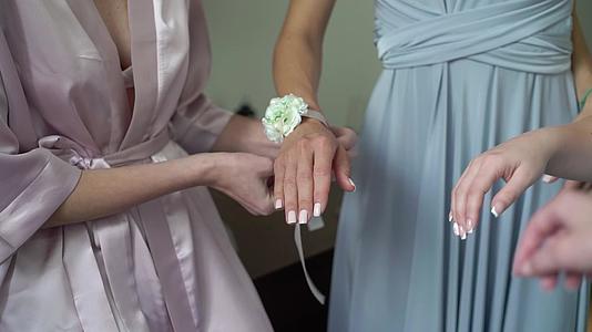 年轻的新娘在伴娘的手腕上戴上鲜花手镯视频的预览图