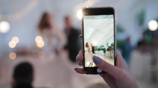 年轻夫妇的婚礼舞蹈新娘和新郎在帐篷派对上用手机跳舞视频的预览图